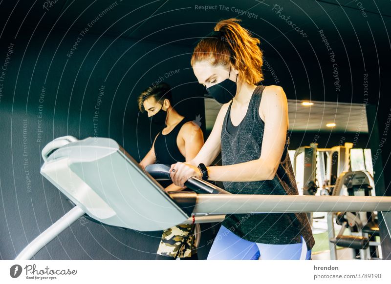 eine junge Frau und ein junger Mann, die eine Gesichtsmaske tragen, trainieren im Fitnessstudio Person Menschengruppe Sport passen Gesundheit Training Club