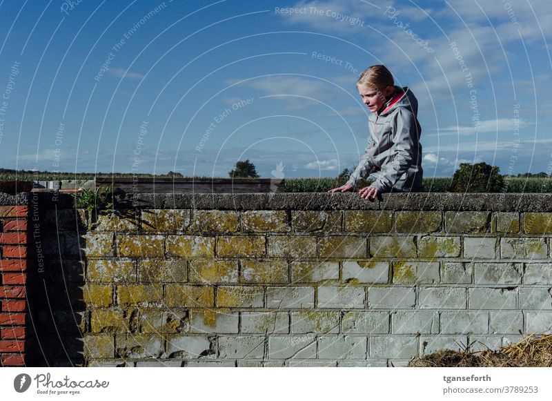 Auf der Mauer Kind Kindheit spielend spielerisch kletternd Mädchen Freude Außenaufnahme Farbfoto Mensch Spielen heiter Porträt mauerwerk Mauerstein alt