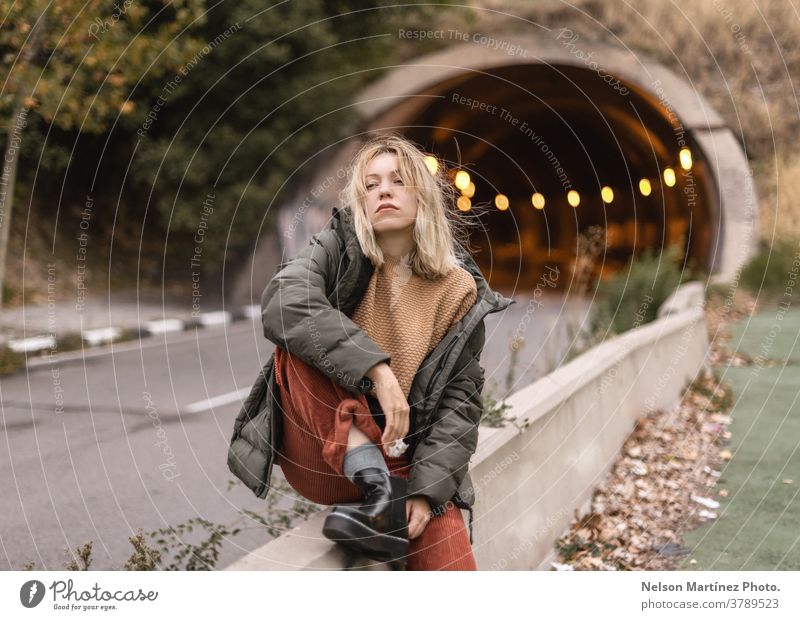 Porträt einer blonden Frau im Herbst, mit einem Tunnel im Hintergrund. Stollen Blätter urban Kaukasier Mode Außenaufnahme Lifestyle Straße Stil hübsch Großstadt