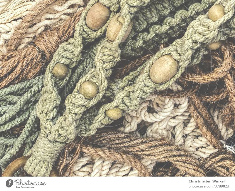 Blick von oben auf mehrere Teile Makramee mit Holzkugeln flechten knüpfen Seile Bänder Schnur Muster Hobby Knoten Naturfarben Handarbeit Grün braun beige