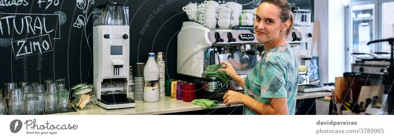 Lächelnde Kellnerin reinigt Kaffeemaschine Reinigen Kaffeehaus schauende Kamera Transparente Kopfball Netz Panorama panoramisch Spültuch Restaurant Kantine