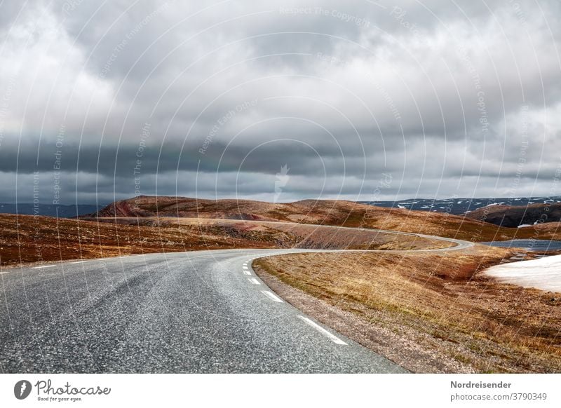 Einsame Landstraße über das Gebirge von Varanger in Norwegen einsamkeit mystik kurve verkehr fjell gebirge hochgebirge varanger norwegen asphalt gras baumlos