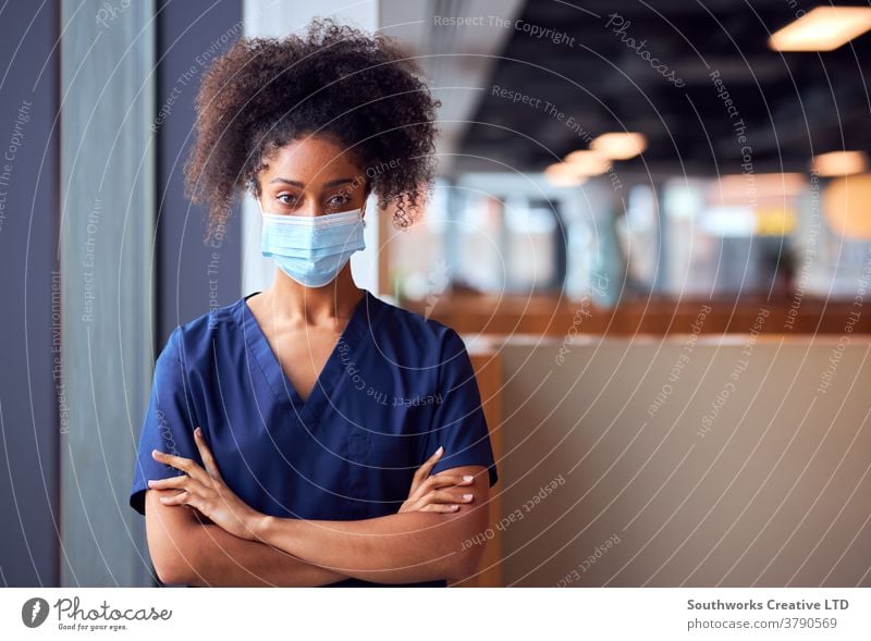 Weibliche Ärztin mit Gesichtsmaske und Kittel unter Druck im geschäftigen Krankenhaus während einer Gesundheitspandemie Arzt Krankenpfleger bürstet