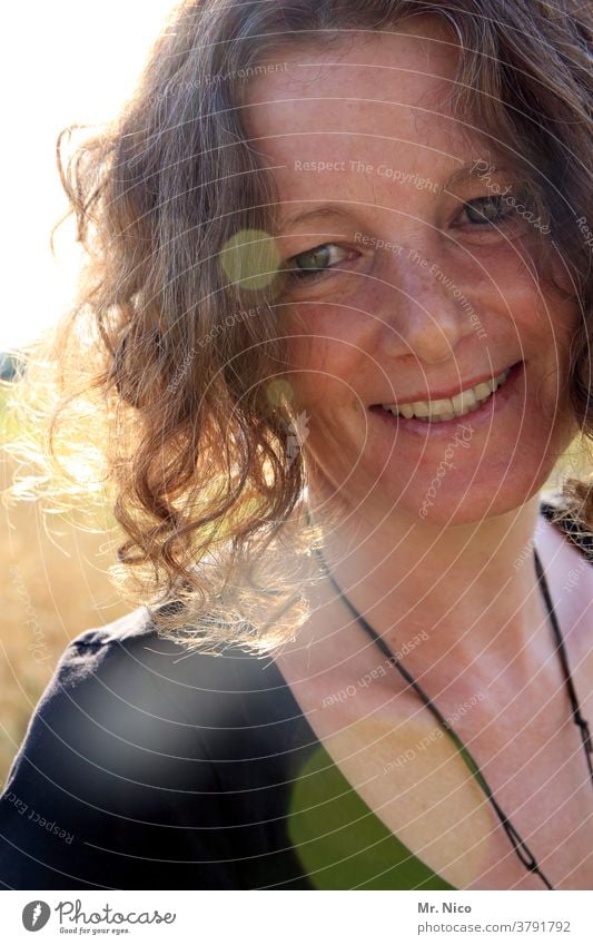 Portrait einer lächelnden Frau im Sonnenlicht Porträt Haare & Frisuren Blick sympathisch Ausstrahlung Freundlichkeit attraktiv Fröhlichkeit Wohlgefühl Kopf