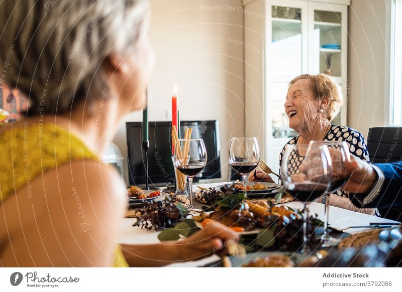 Lachende Frauen interagieren am Tisch während des Weihnachtsessens Lebensmittel Weihnachten Abendessen Alkohol Freund Lächeln feiern festlich flach Rotwein