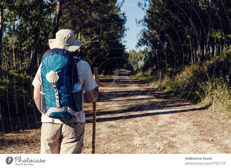 Gesichtsloser Tourist mit Rucksack und Trekkingstock auf schäbigem Weg Mann Pilgerfahrt Route kleben reisen Santiago de Compostela erkunden camino de santiago