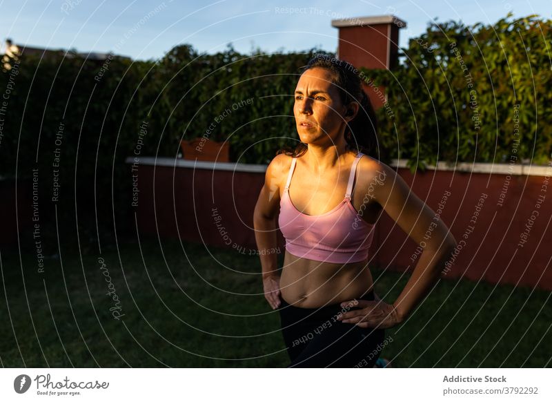 Schlanke Frau macht Übungen im Innenhof im Sommer Ausfallschritt Training Laptop online Tutorial benutzend Athlet Sonnenuntergang Sportbekleidung Gesundheit
