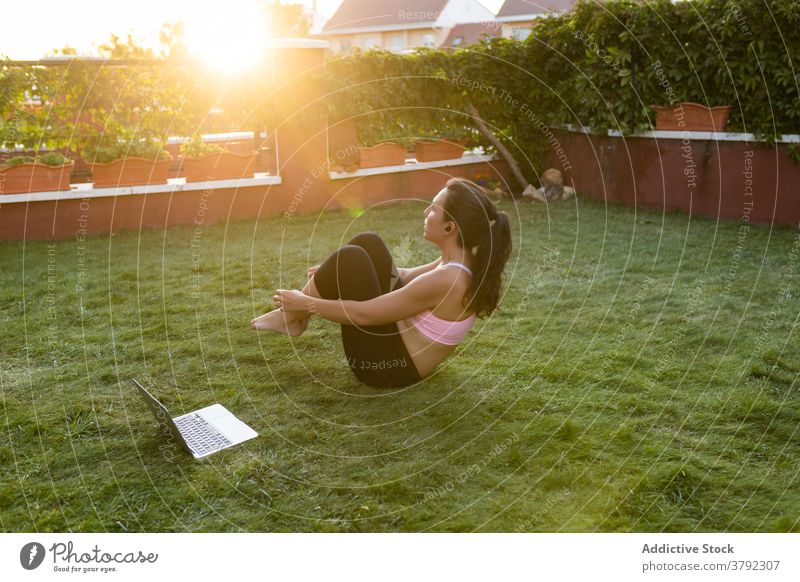 Ausdauernde Frau beim Bauchmuskeltraining im Sommer Bauchmuskeln Training Unterleib knirschen Athlet online Tutorial Laptop benutzend passen Gesundheit Übung