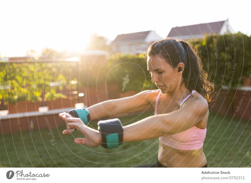 Schlanke Frau macht Übungen im Innenhof im Sommer Training Kniebeuge Laptop online Tutorial benutzend Athlet Sonnenuntergang Sportbekleidung Gesundheit Fitness
