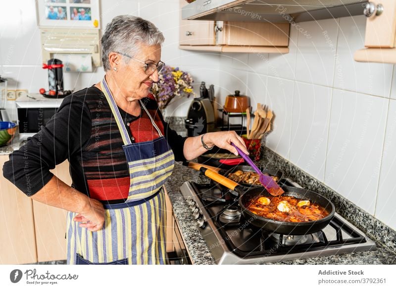 Reife Frau kocht Fischgericht zu Hause Koch schmoren Saucen vorbereiten Lebensmittel Prozess Küche Meeresfrüchte Dorsch Hausfrau kulinarisch Herd Pfanne Rezept
