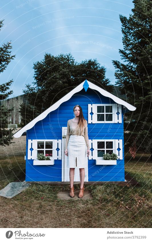 Attraktive Frau steht in der Nähe von kleinen blauen Haus selbstbewusst cool Stil Vorschein trendy Park Windstille Konstruktion emotionslos ruhig traumhaft
