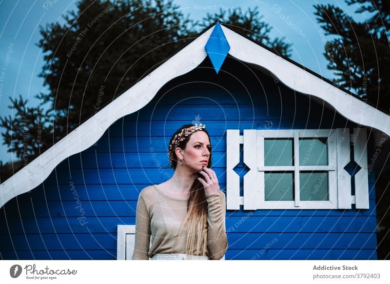 Attraktive Frau steht in der Nähe von kleinen blauen Haus selbstbewusst cool Stil Vorschein trendy Park Windstille Konstruktion emotionslos ruhig traumhaft
