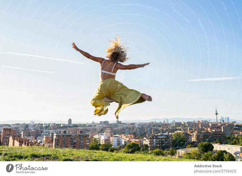 Gesichtslose energiegeladene Frau springt auf Stadtschanze springen Aktivität Energie Arme hochgezogen sorgenfrei Freude aufgeregt Sprung Bergkuppe Vitalität