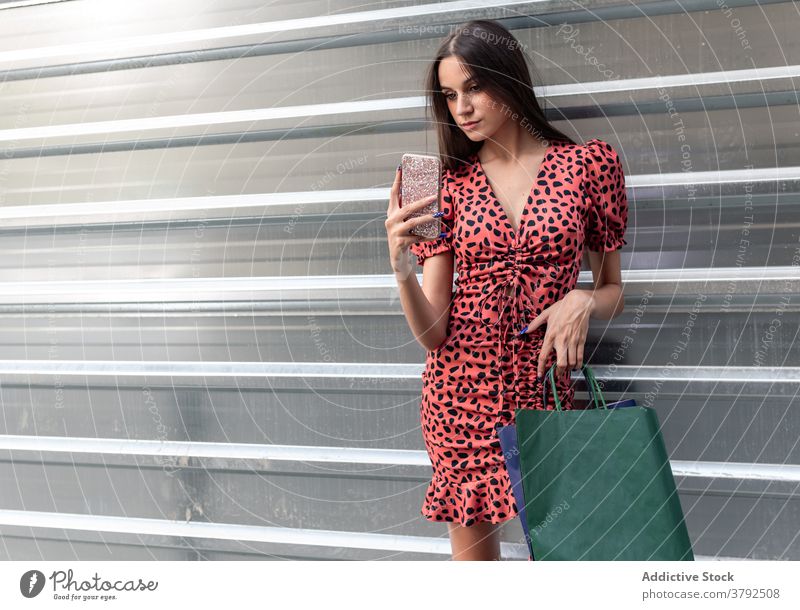 Frau textet auf Smartphone auf der Straße Nachricht benutzend Großstadt soziale Netzwerke jung Metall Wand online Apparatur Gerät charmant Texten Handy