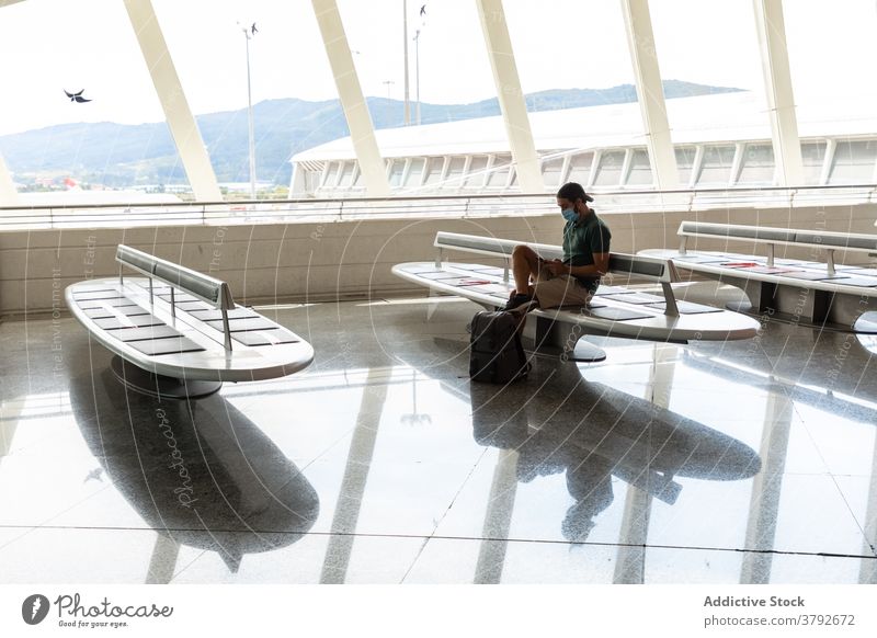 Reisender Mann sitzt im Flughafen Abheben räkeln Smartphone sprechen Mundschutz Bund 19 benutzend Projekt männlich Tourist reisen Ausflug Gerät Apparatur Mobile