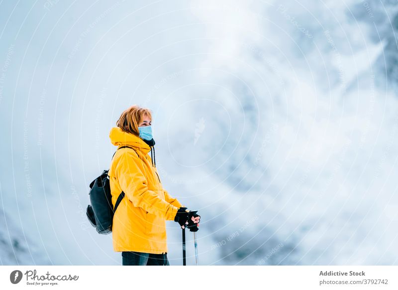 Wanderer mit Schutzmaske auf verschneitem Gelände stehend Trekking Reisender Mundschutz Coronavirus aktiv Schnee Berge u. Gebirge Rucksack Abenteuer COVID19