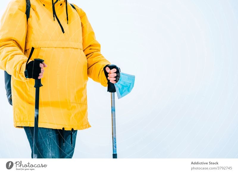Wanderer mit Schutzmaske auf verschneitem Gelände stehend Trekking Reisender Mundschutz Coronavirus aktiv Schnee Berge u. Gebirge Rucksack Abenteuer COVID19