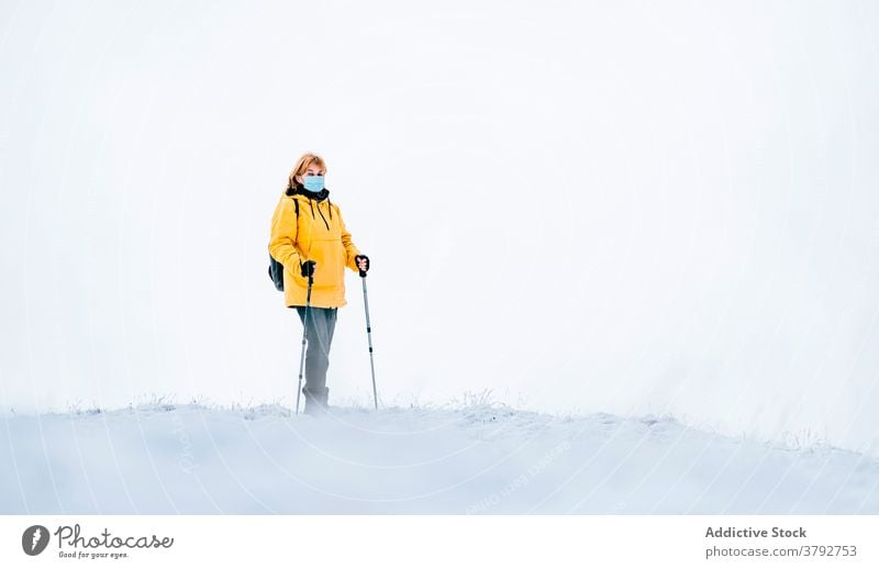 Aktiver Reisender in warmer Kleidung und medizinischer Maske in verschneiten Bergen Wanderer Trekking Mundschutz COVID19 Coronavirus aktiv Schnee