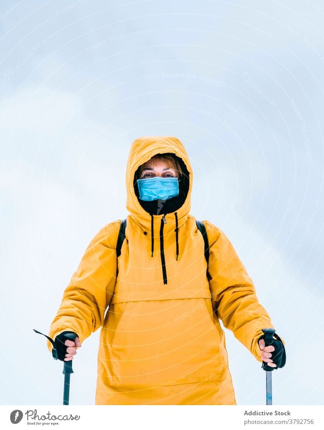Aktiver Reisender in warmer Kleidung und medizinischer Maske in verschneiten Bergen Wanderer Trekking Mundschutz COVID19 Coronavirus aktiv Schnee