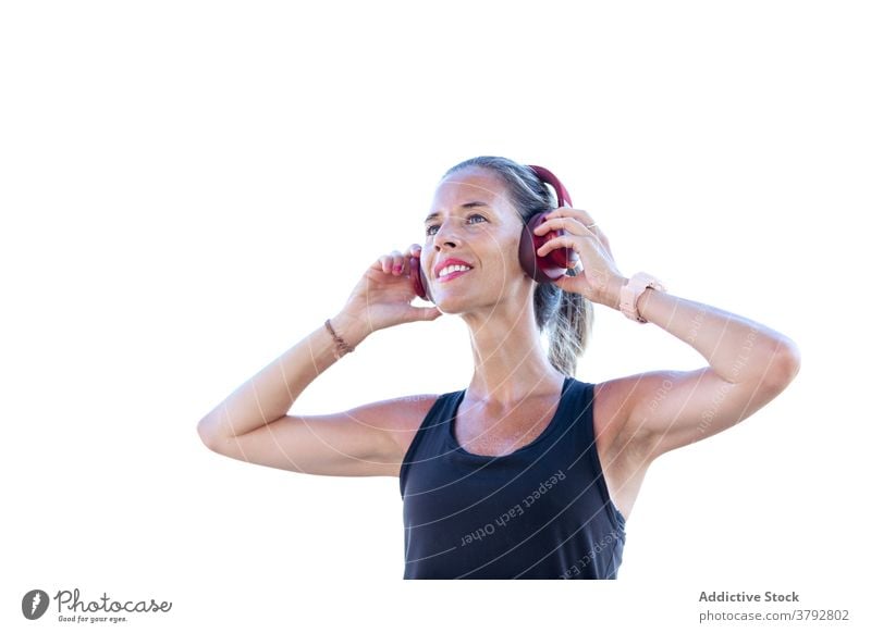 Fröhliche Frau hört Musik in modernen Kopfhörern zuhören Optimist Gerät heiter Glück Audio Lächeln Melodie Klang Podcast unterhalten Gesang Sonnenbrille jung