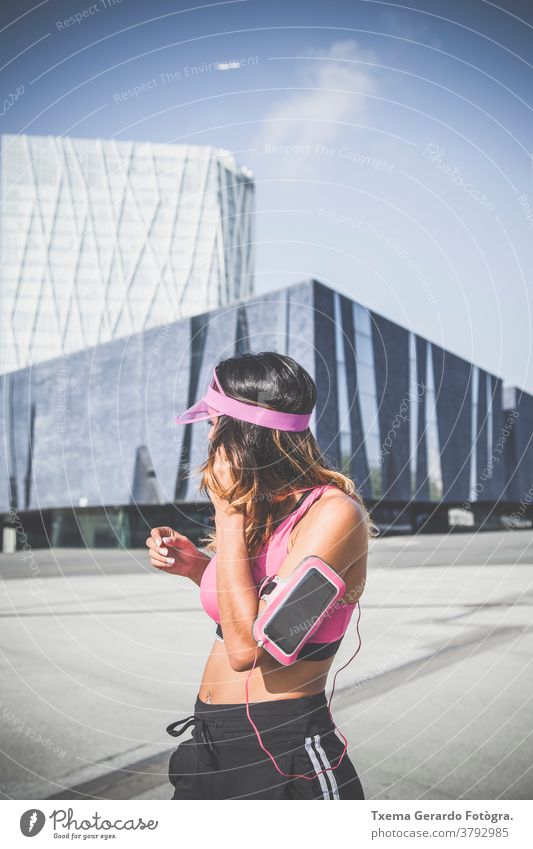 Mädchen hört Musik auf ihrer Armbinde mit Touchscreen und Kopfhörern in Barcelona Sportkleidung Erwachsener Arme sportlich rennen Läufer Übung Herz Fitness Frau
