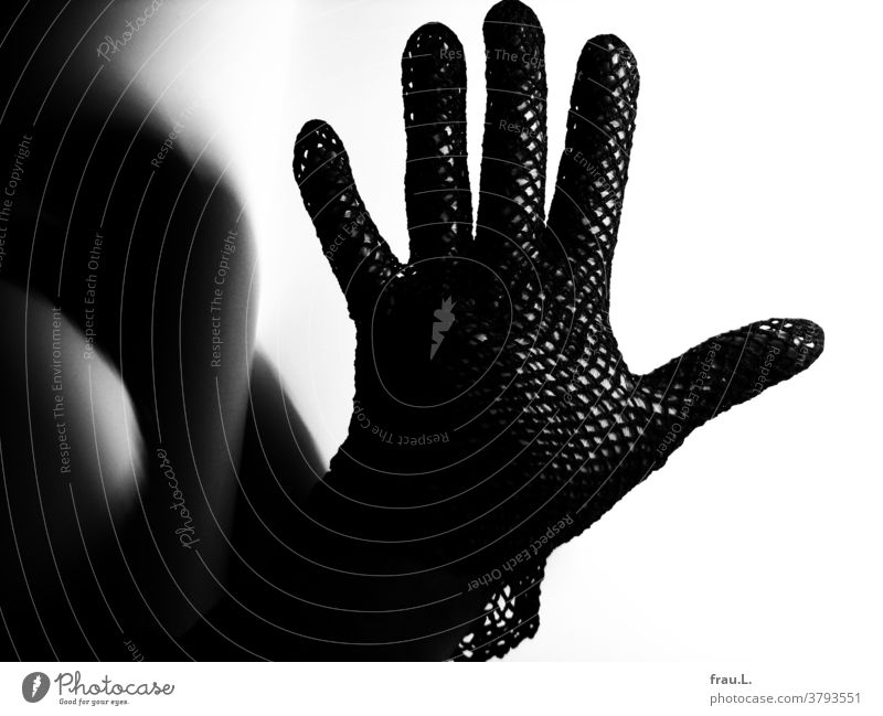 Einsamer Netzhandschuh an einsamer Frauenhand. Handschuh Schatten Finger schwarz Haut