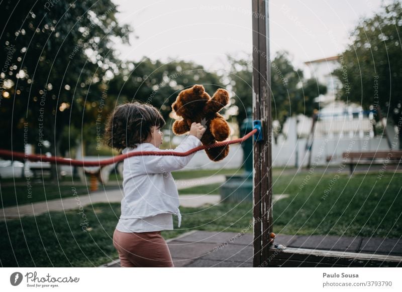Kleines Mädchen spielt mit Teddybär auf dem Spielplatz Park Kind Kindheit Bär Spielzeug niedlich Freude klein Spielen braun Farbfoto Außenaufnahme Puppe weiß