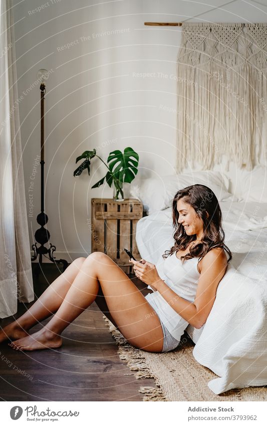 Attraktive Frau in Nachtwäsche mit Smartphone im Schlafzimmer Browsen Freude benutzend Funktelefon Gerät Glück Bett gemütlich Inhalt Apparatur brünett jung