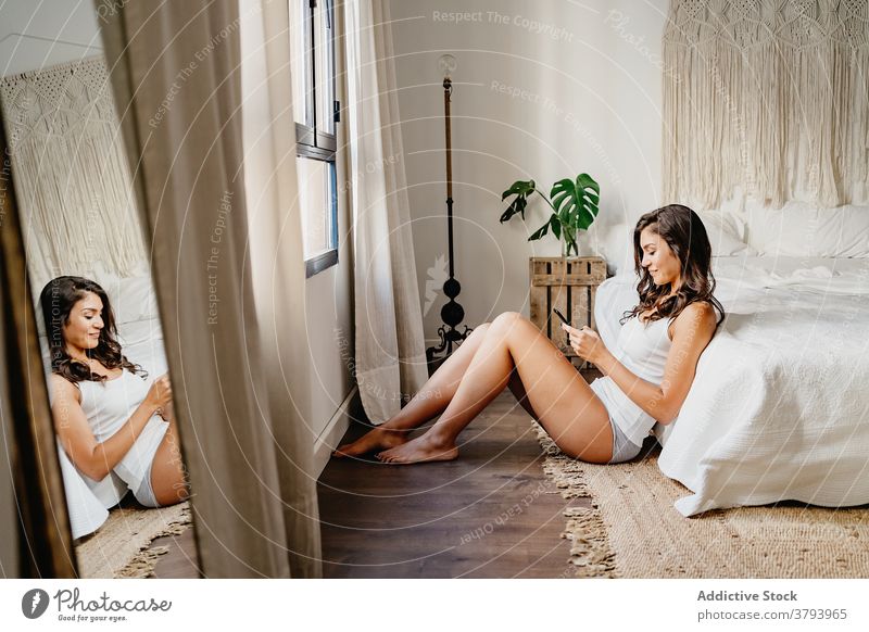 Attraktive Frau in Nachtwäsche mit Smartphone im Schlafzimmer Browsen Freude benutzend Funktelefon Gerät Glück Bett gemütlich Inhalt Apparatur brünett jung