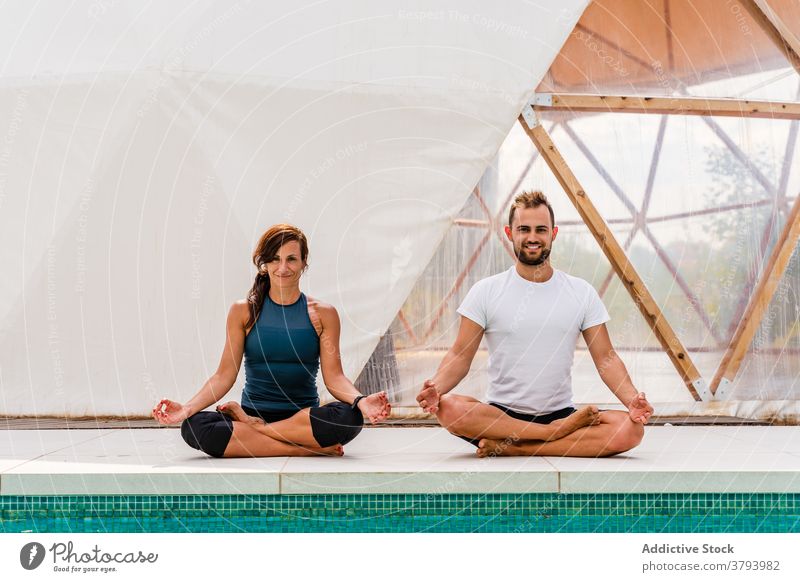 Paar sitzt in Lotus-Pose, während reflektierend in Schwimmbad Yoga üben Reflexion & Spiegelung Schwimmsport Pool Wohlbefinden Sprit Stressabbau Wellness Zelt