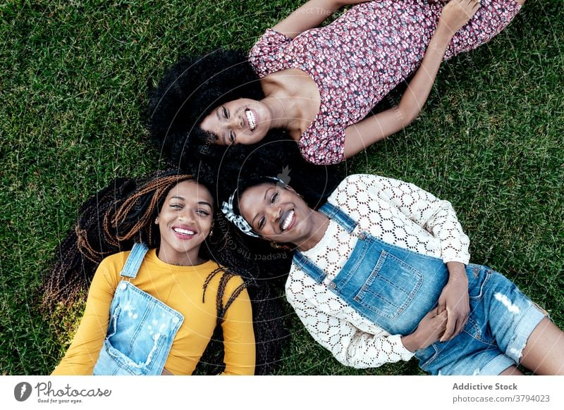 Positive unterschiedliche Frauen liegen auf Gras im Park Freundschaft Lügen positiv Zusammensein freundlich Bonden jung multiethnisch rassenübergreifend