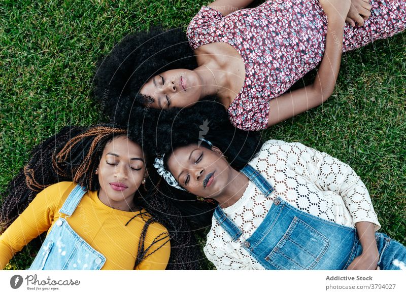 Diverse Frauen liegen auf Gras im Park Freundschaft Lügen positiv Zusammensein freundlich Bonden jung multiethnisch rassenübergreifend vielfältig schwarz