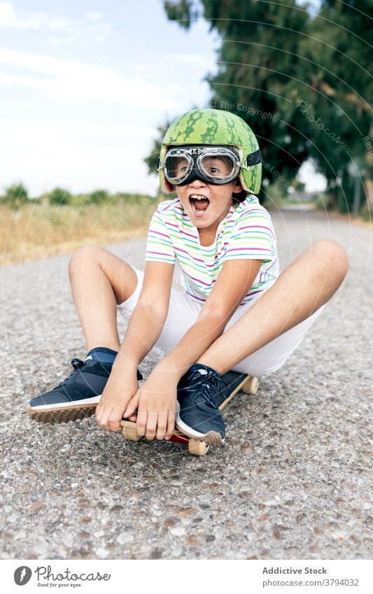 Glücklicher Junge auf Skateboard in Schutzbrille Schutzhelm Spaß haben sorgenfrei Kindheit aufgeregt Inhalt Straße stylisch Bekleidung Brille dekorativ Sommer