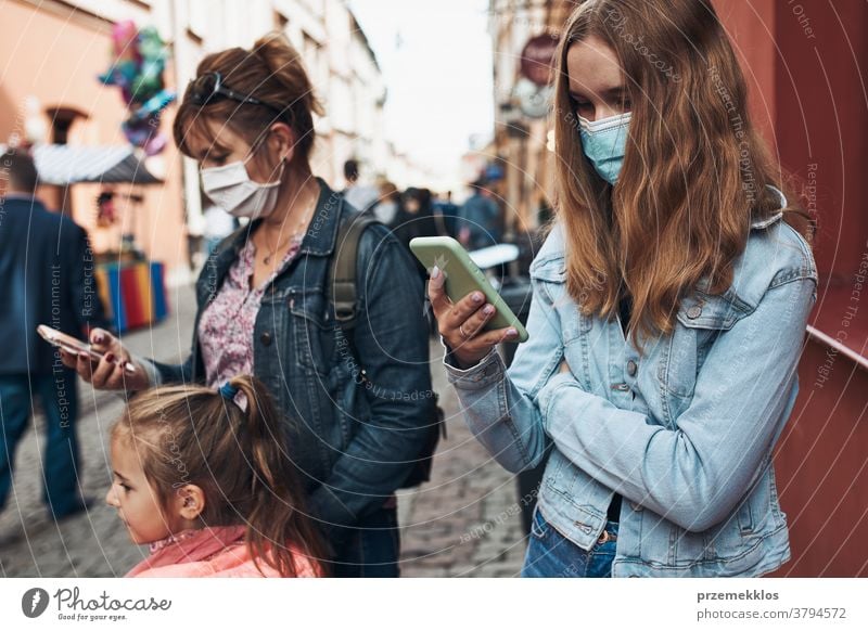 Junge Frauen, die Smartphones benutzen und auf einer Straße in der Innenstadt stehen und die Gesichtsmasken tragen, um eine Virusinfektion zu vermeiden Anruf