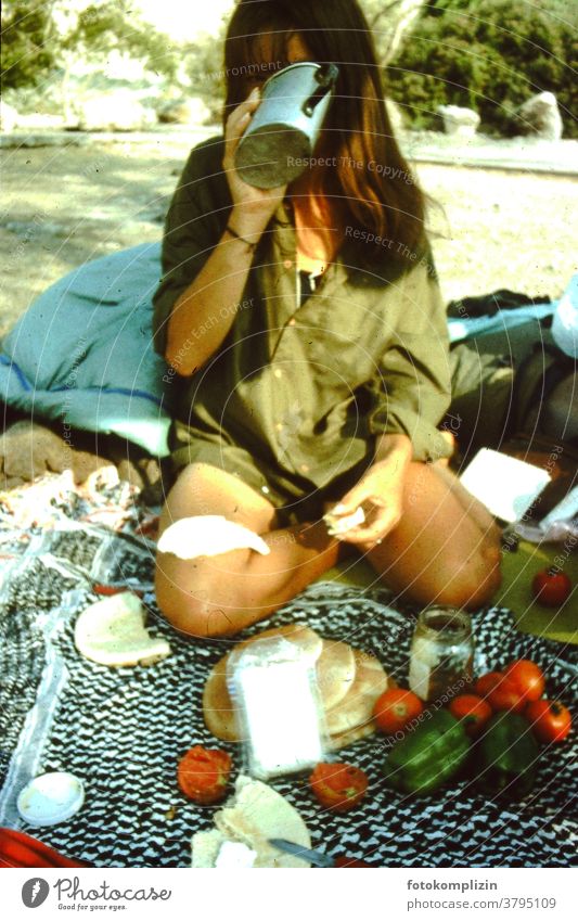 Frau auf dem Boden sitzend mit einem Picknick Picknickdecke trinken Weltenbummler reisend Camping einfach einfaches Leben außerhalb im Freien Lager Ausflug
