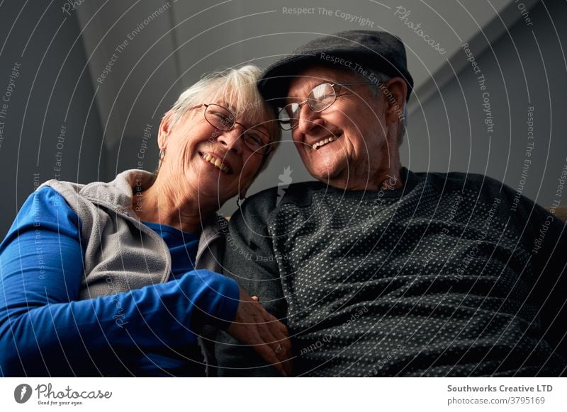 Lachendes Senior-Paar sitzt zu Hause auf dem Sofa und sieht gemeinsam fern Senioren in den Ruhestand getreten zuschauend FERNSEHER Fernsehen Sitzen Zusammensein