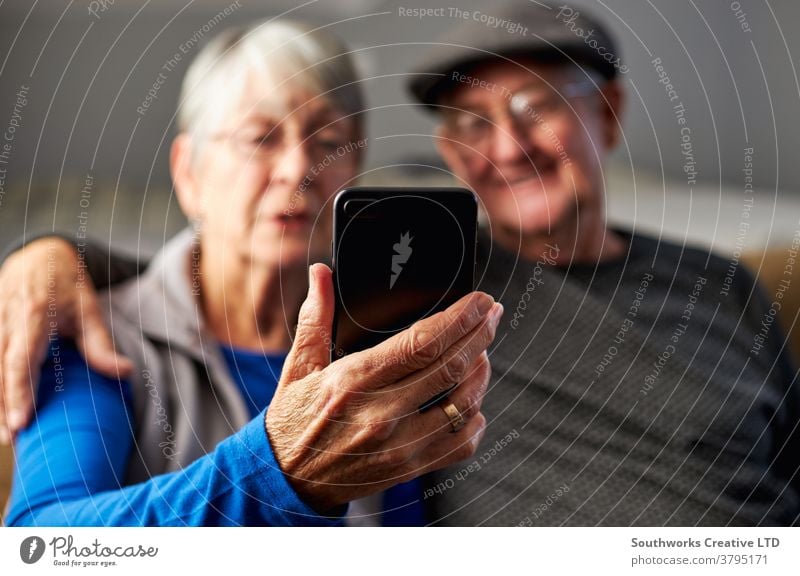 Älteres Ehepaar zu Hause macht einen Videoanruf mit der Familie am Mobiltelefon Paar Senior Senioren Video-Chat Mobile Handy Zelle verbunden online Technologie