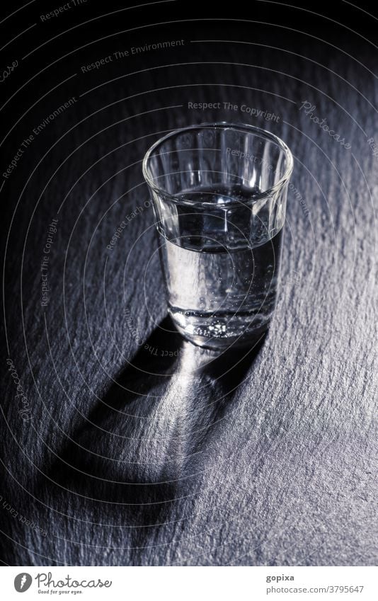 Ein Glas Wasser mit Schatten Trinkglas Trinkwasser Mineralwasser Lebensmittel Nahrungsmittel Gesundheit Durst einfach dunkel Dunkelheit karg Getränk