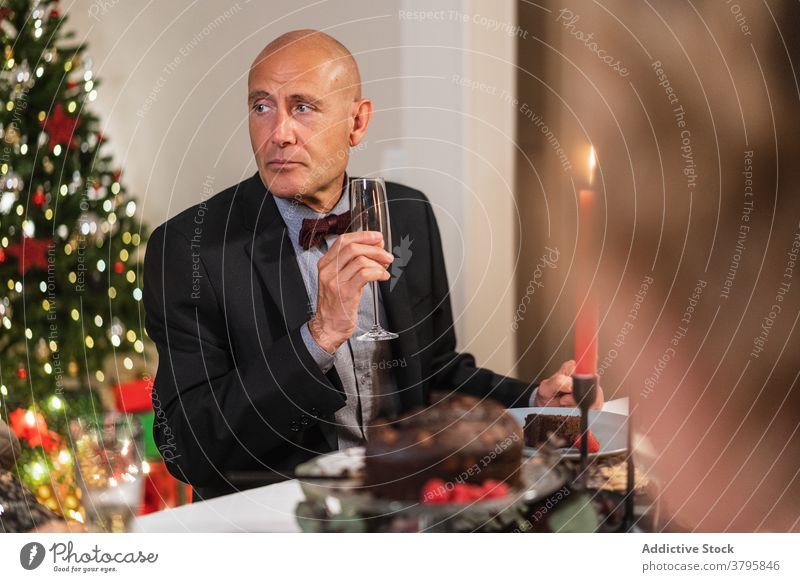 Eleganter Mann am Weihnachtstisch zu Hause Weihnachten Tisch Festessen Champagne elegant Feiertag reif feiern festlich männlich ernst Party fröhlich Alkohol