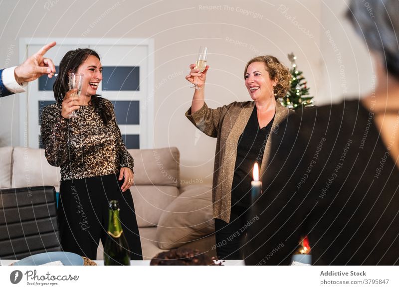 Entzückte Frauen feiern Weihnachten zu Hause Party trinken Champagne Zuprosten jubelt Zusammensein gemütlich Outfit Unternehmen festlich Menschen heiter