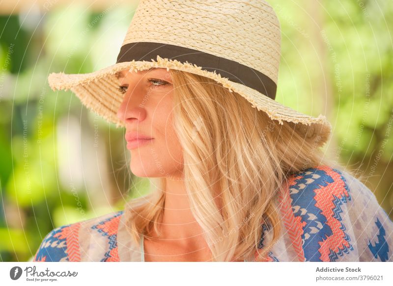 Nachdenkliche junge Frau mit Strohhut schaut im Sonnenlicht weg verträumt sich[Akk] entspannen Feiertag Sommer Stil Mode ruhen Reisender Natur grün Garten blond