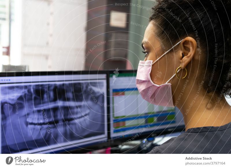 Ethnischer Zahnarzt mit Maske bei der Untersuchung eines Röntgenbildes im Krankenhaus untersuchen dental Zähne Frau Arzt Stomatologie Monitor Computer ethnisch