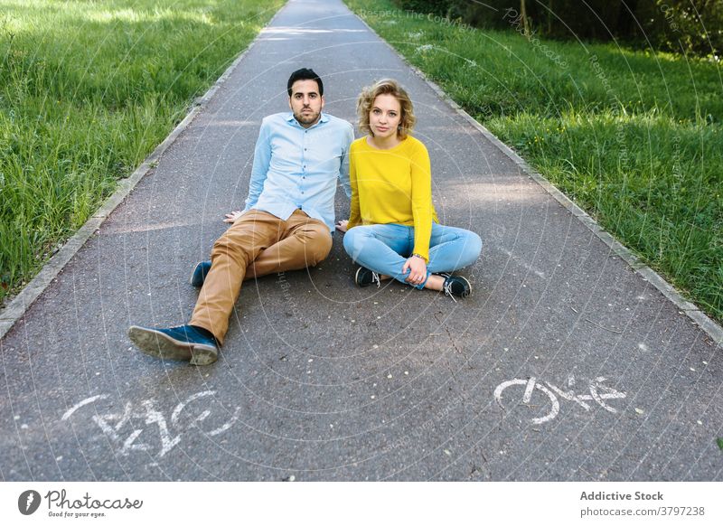 Unbekümmertes Paar auf Asphaltstraße im Park Straße sorgenfrei Partnerschaft sich[Akk] entspannen Laufsteg Sommer trendy grün Outfit Zusammensein sitzen