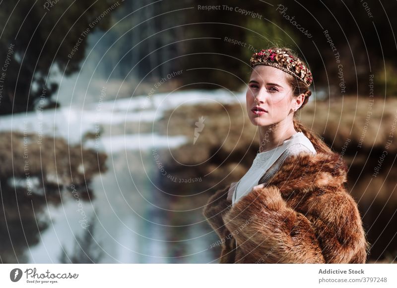 Elegante Frau in Pelzkleidung und Blumenkranz stehend in der Natur Fell Totenkranz nordisch Tradition Mode Stil Outfit feminin sinnlich verträumt Hochzeit
