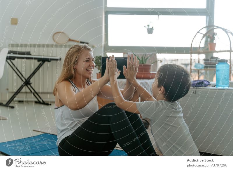 Junge hilft Mutter bei der Durchführung von Curl ups zu Hause sich[Akk] zusammenrollen Bauchmuskeln Training ausführen knirschen high five heiter Übung