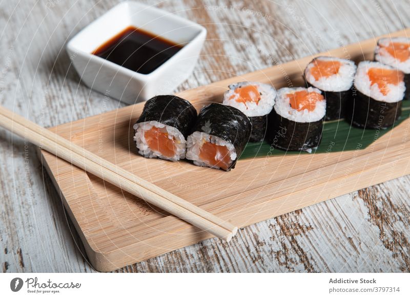 Sushi-Rollen mit Lachs auf Holzbrett rollen hosomaki Japanisch Lebensmittel Meeresfrüchte Fisch Tradition Kulisse frisch Mahlzeit Küche Speise Feinschmecker