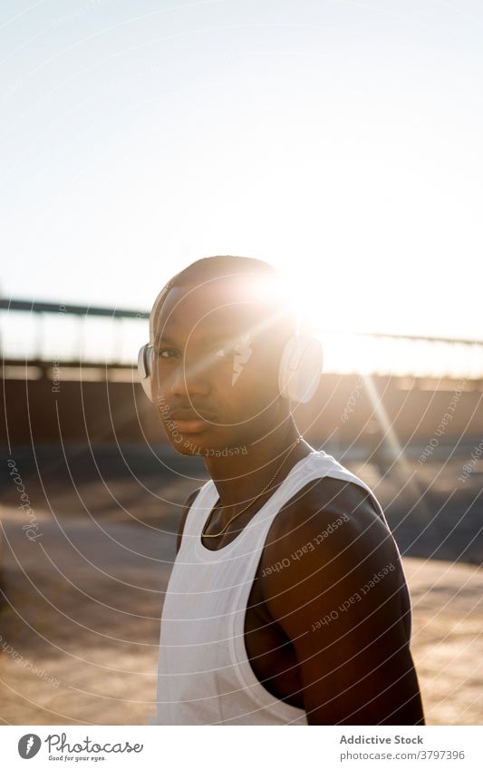 Schwarzer sportlicher Mann beim Musikhören Läufer anonym benutzend Kopfhörer zuhören Training Athlet Pause Sportler Apparatur Sportbekleidung Drahtlos Lifestyle