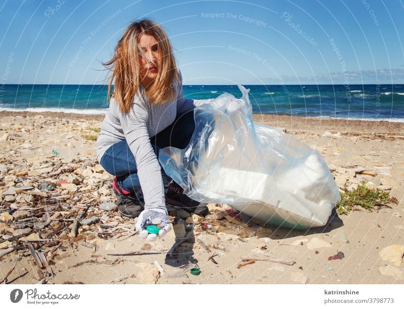 Junge Frau reinigt Strandbereich und zeigt Plastikflaschendeckel in der Hand jung Reinigen Gegend Kunststoff Tasche MEER Flasche Deckel sammelnd Natur