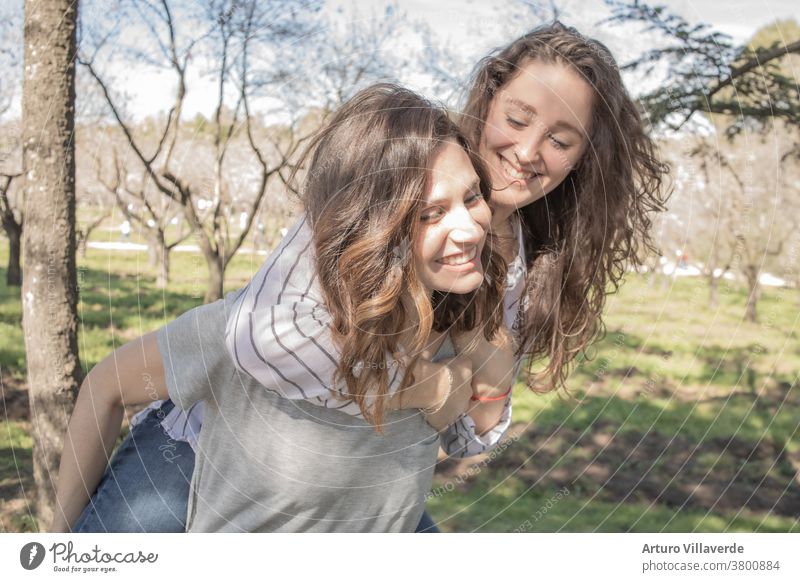 zwei Mädchen einen Park von Mandelbäumen, die zusammen lachend aufeinander kletterten Aktivität Hintergrund schön hell nachlässig heiter farbenfroh Frau Freunde