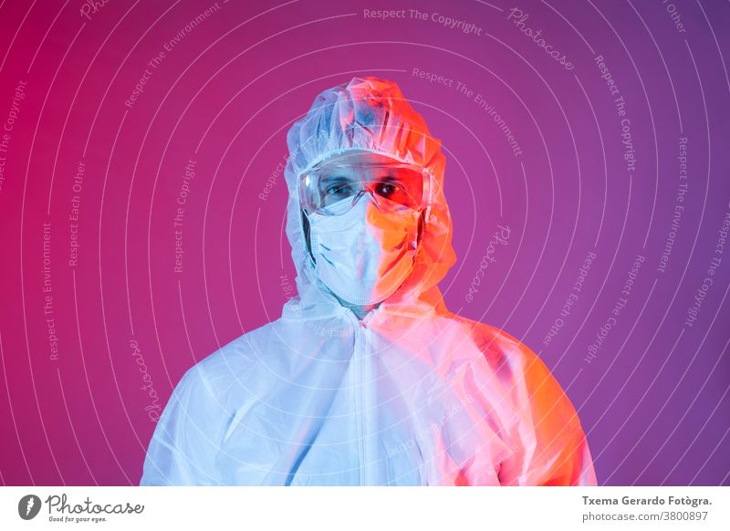 Bildnis eines Mannes mit chemischer Schutzausrüstung für Covid-19 vor farbigem Hintergrund Mundschutz Coronavirus Sicherheit Desinfektion Krankheit Arzt Seuche